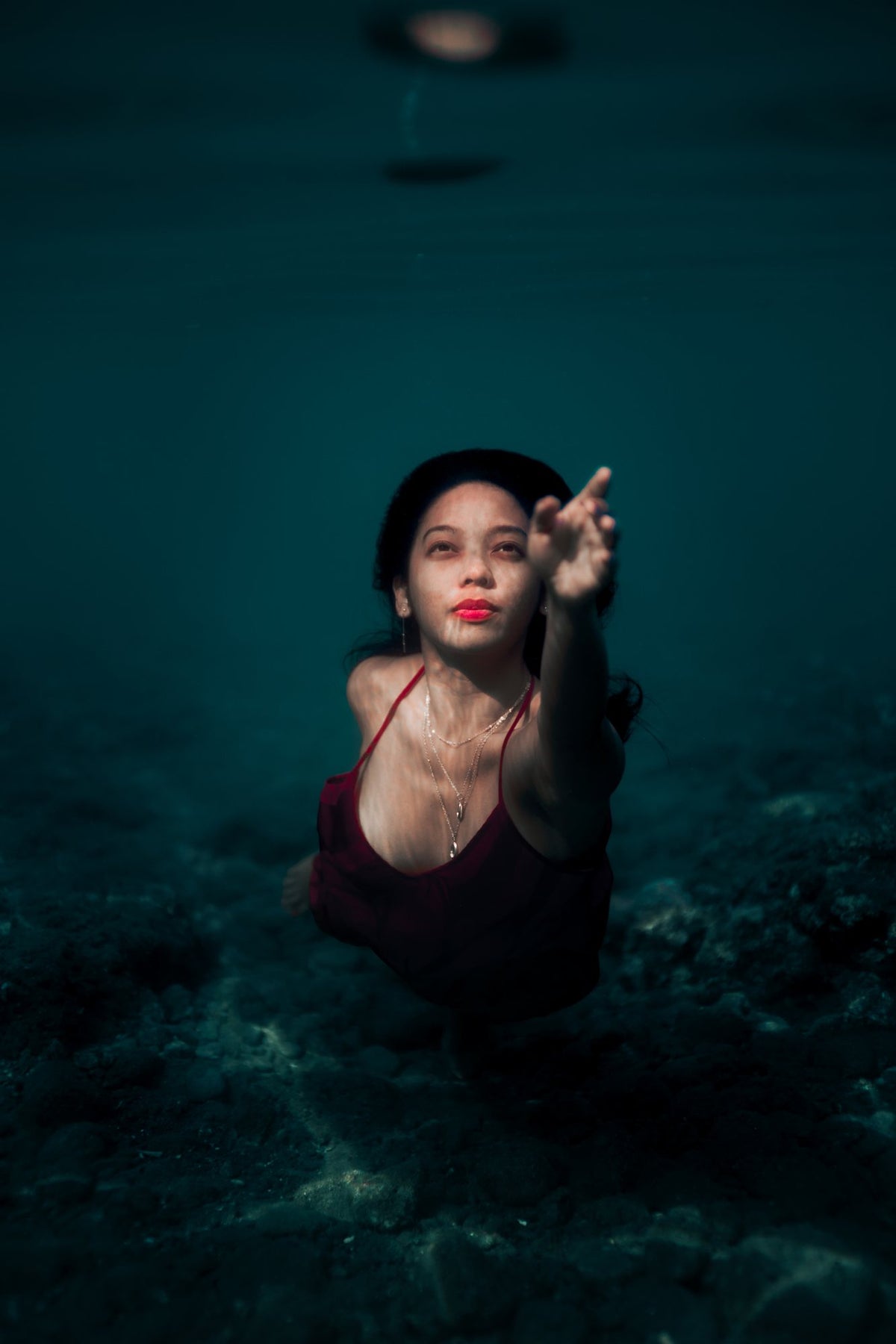 Kaye reaching out underwater, sunlight filtering through the water