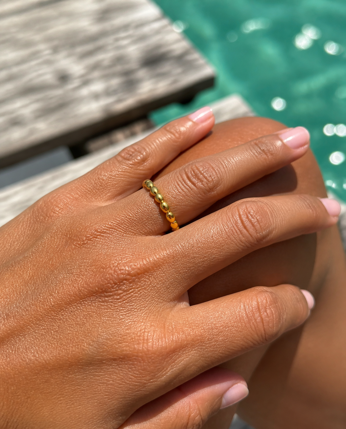 Beaded gold ring worn on a dock, close-up