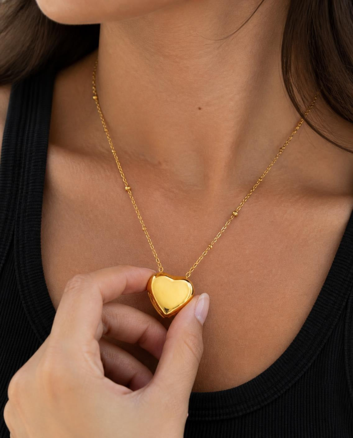 Close-up of the Puffy Heart pendant held between fingers