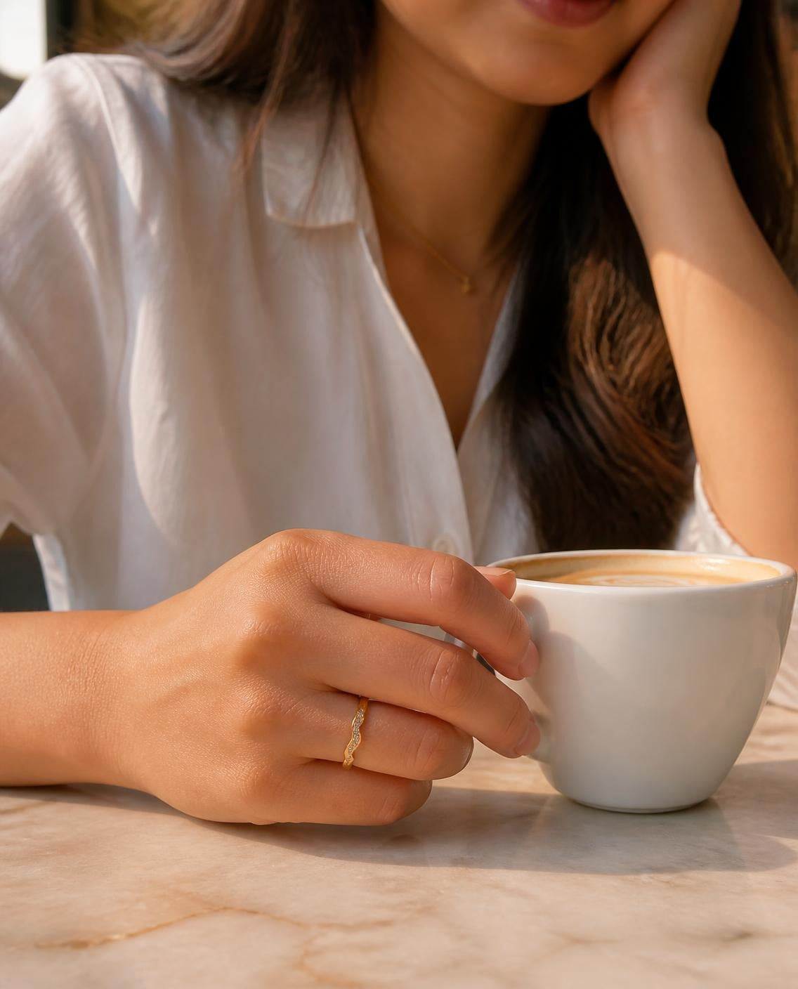 Hand holding a coffee cup wearing the Textured Band Ring