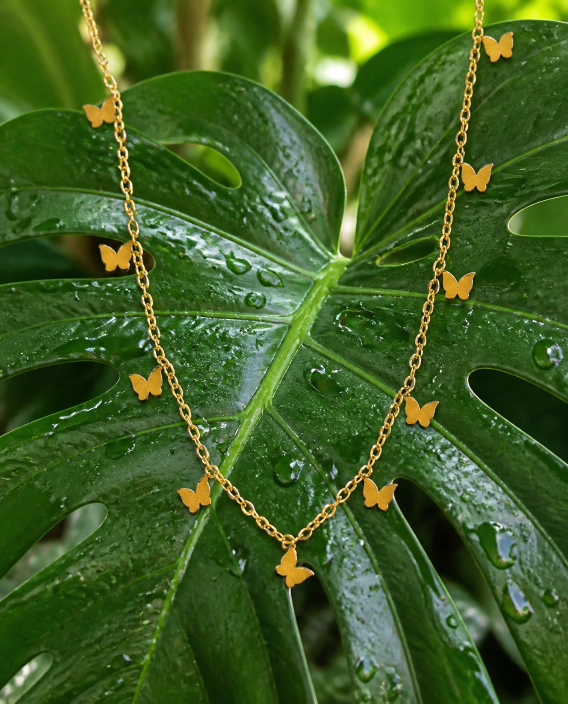 Butterfly Charm Necklace on a monstera leaf
