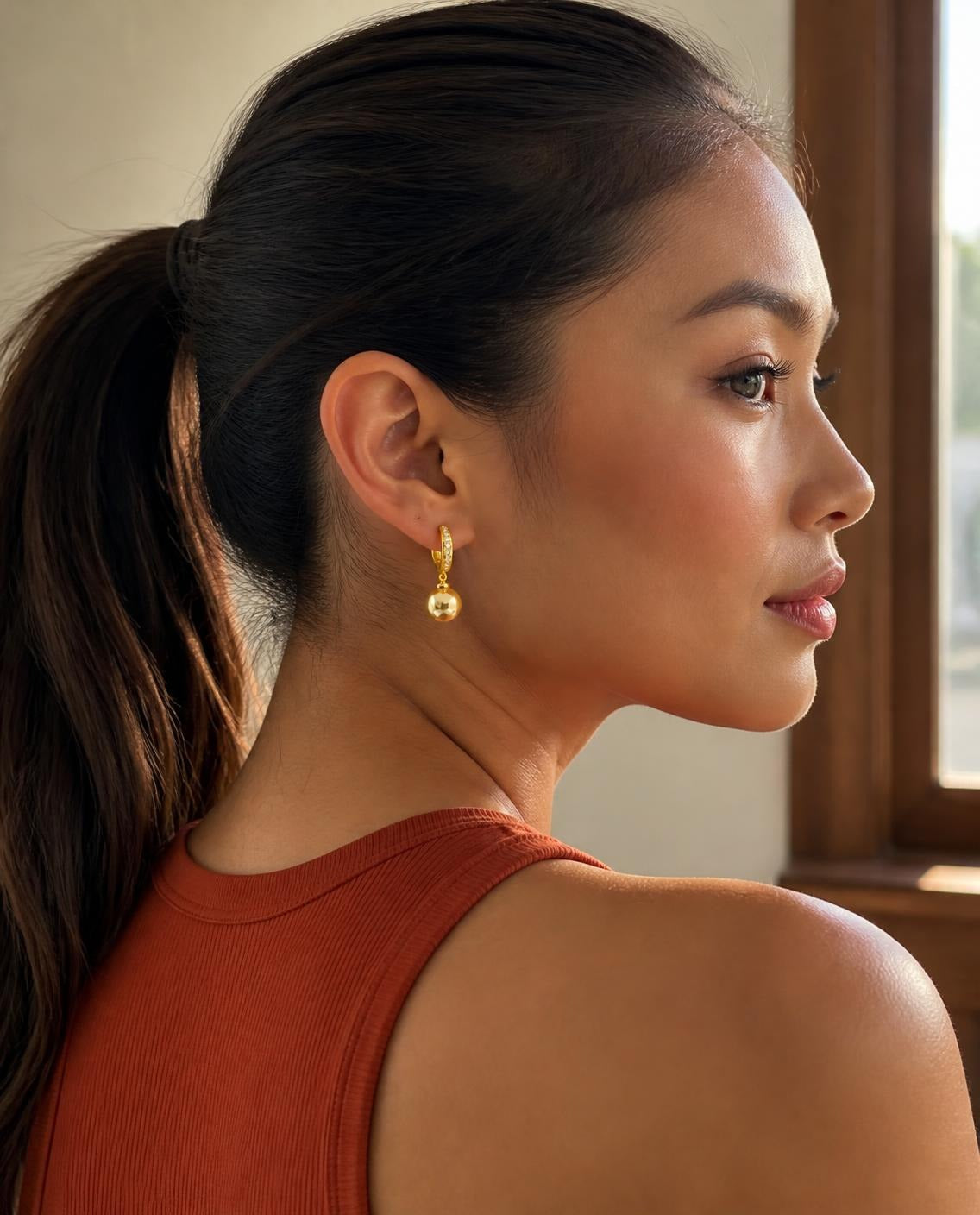 Model with a high ponytail wearing the Golden Pearl Drop Hoops