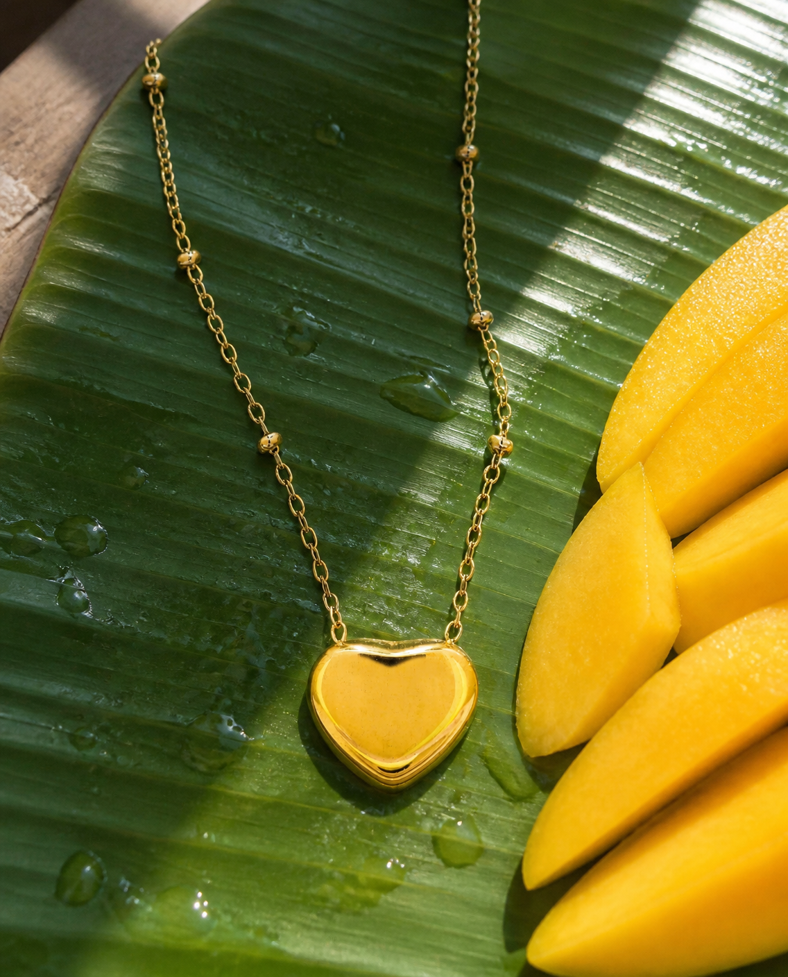 Puffy Heart Necklace on a banana leaf with mango