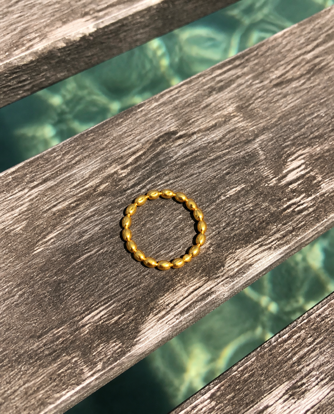 Beaded gold ring on a pier plank over the sea