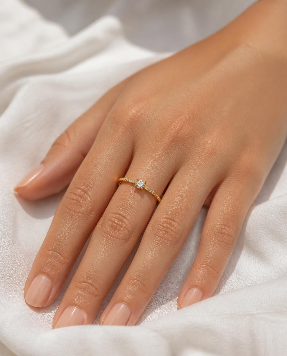 Hand on white linen wearing the Thin Solitaire Ring