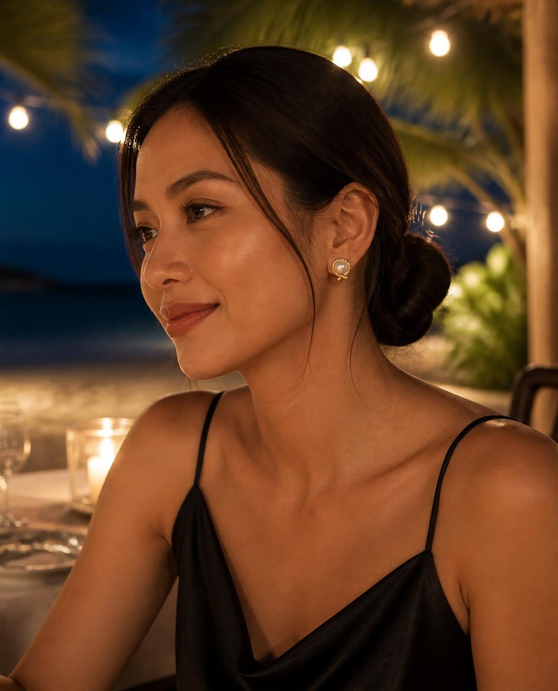 Model at an evening beach dinner wearing the Pearl Wrap Stud Earrings