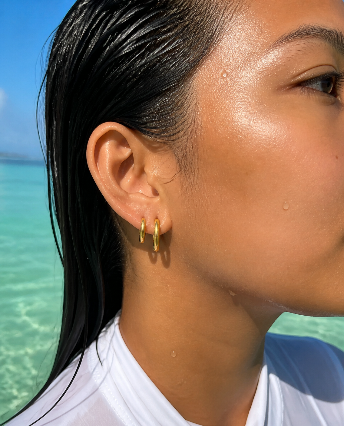 Classic Huggie Hoops worn as an ear stack in the sea