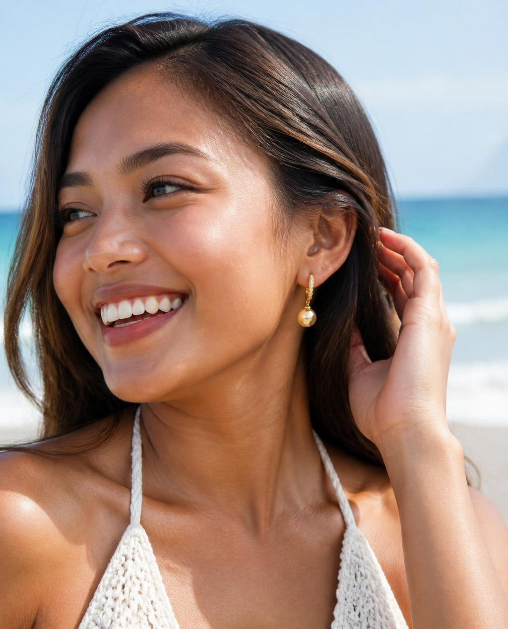 Laughing model on the beach wearing the Golden Pearl Drop Hoops