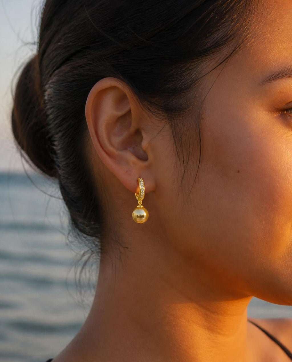 Side profile of a model wearing the Golden Pearl Drop Hoops at golden hour