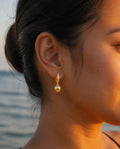Side profile of a model wearing the Golden Pearl Drop Hoops at golden hour