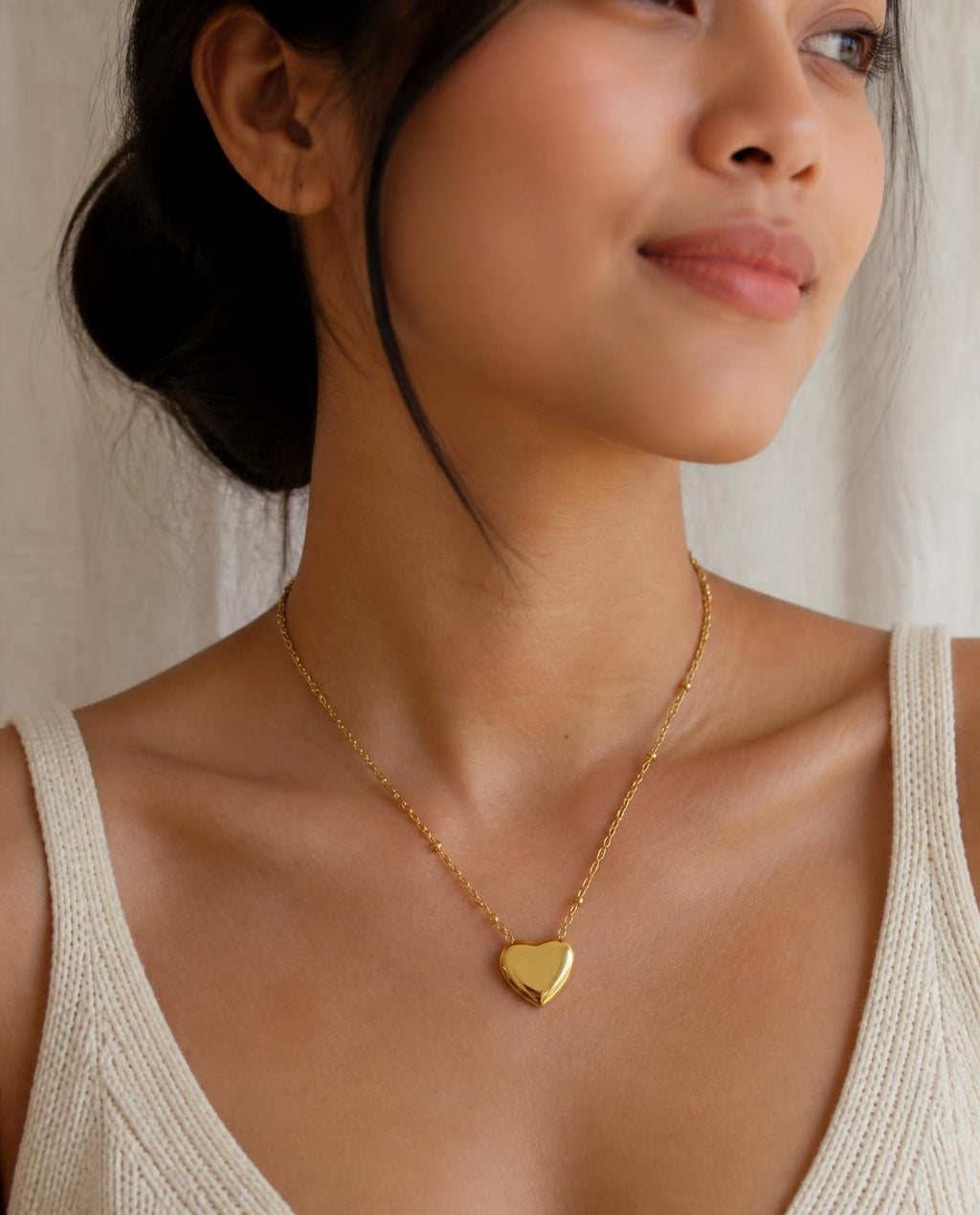 Model wearing the Puffy Heart Necklace with a cream knit top