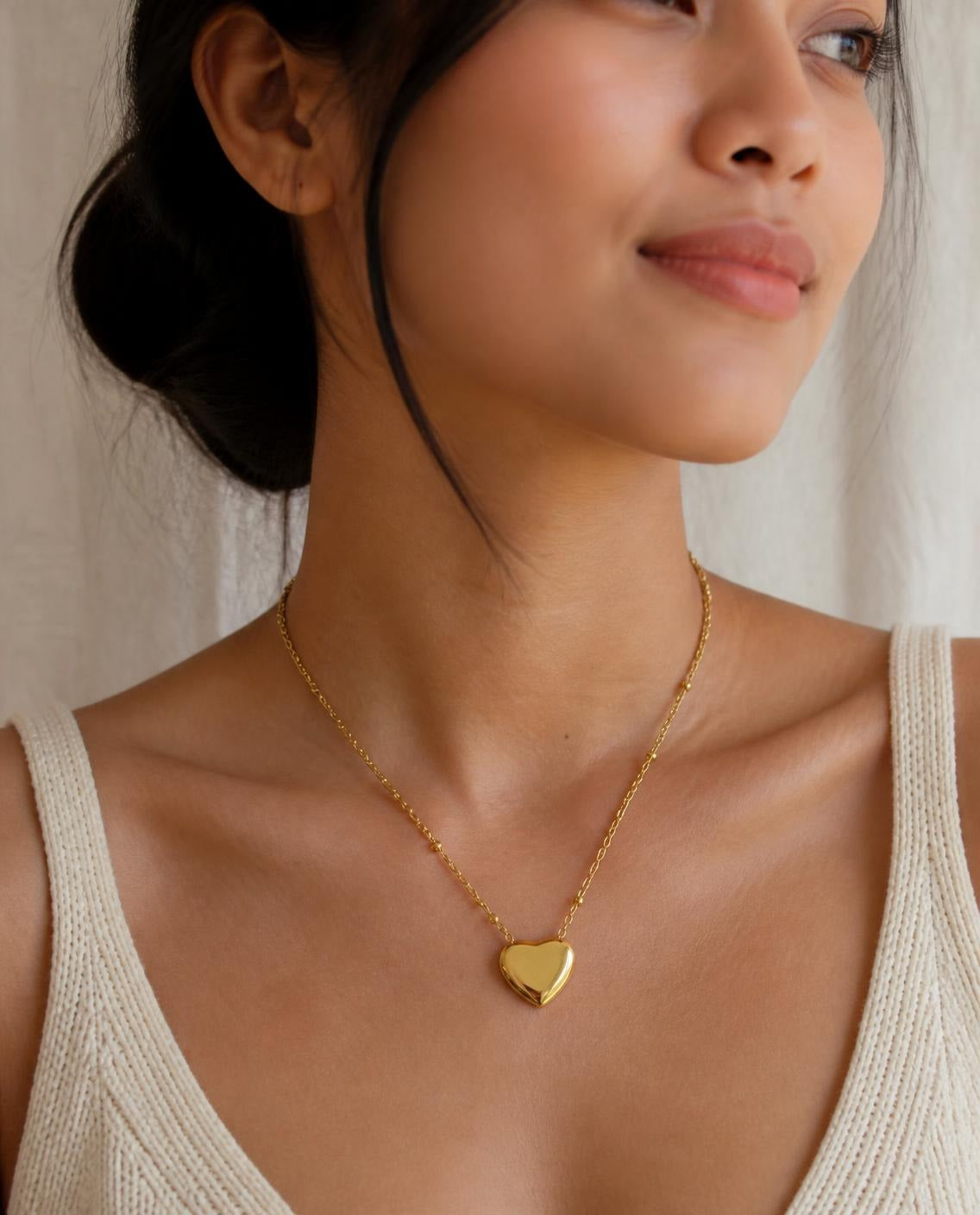 Model wearing the Puffy Heart Necklace with a cream knit top