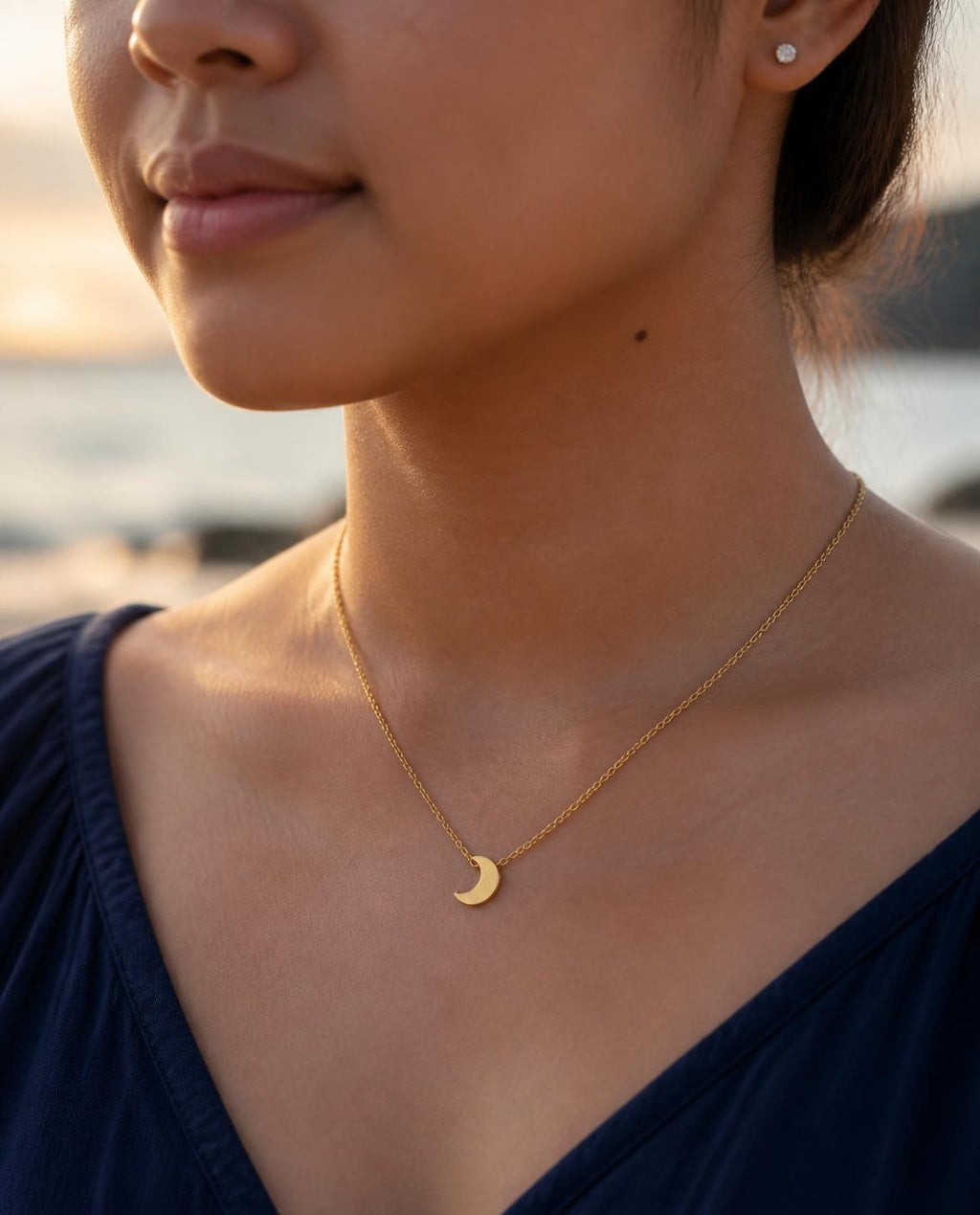Model wearing the Crescent Moon Necklace by the sea at dusk