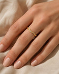 Hand on beige linen wearing the Textured Band Ring